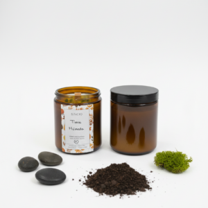 Vela artesanal Tierra Húmeda de cera de soja junto a tierra, musgo y piedras naturales, inspirada en el aroma del bosque después de la lluvia.